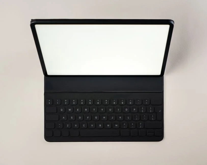 Un espace de travail épuré et moderne avec un ordinateur portable, une tablette, un smartphone et un écran. Idéal pour le télétravail et les installations technologiques.